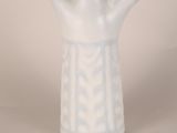 a white vase sitting on a table with a white wall in the background