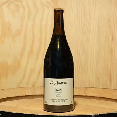 a bottle of wine sitting on top of a wooden barrel