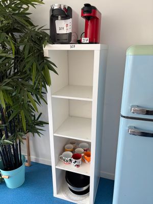 une grande étagère blanche sur laquelle se trouvent une bouteille de vin et une plante en pot