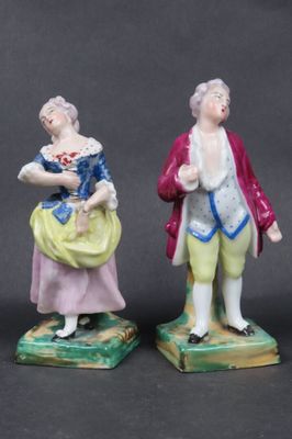 two figurines of a man and a woman standing next to each other