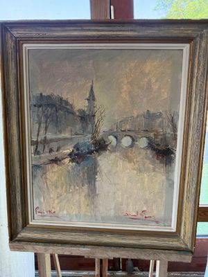 painting on easel in front of a window with a view of a bridge