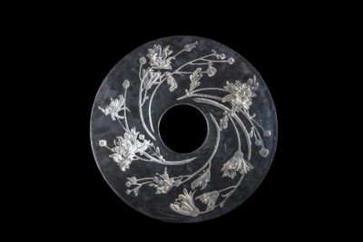 a black and white picture of a circular object with flowers on it