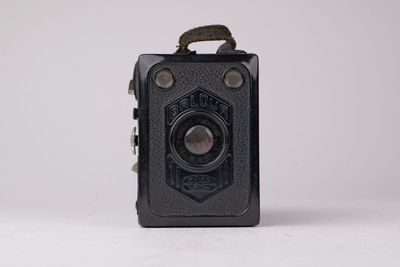 un vieil appareil photo noir posé sur une surface blanche