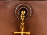 the handle of a brown purse with a gold chain hanging from it