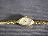 a close up of a gold wrist watch with a chain around it