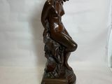 statue en bronze représentant une femme assise sur un rocher, les mains posées sur les genoux