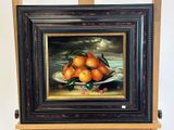 une peinture représentant des oranges dans une assiette, posée sur un chevalet