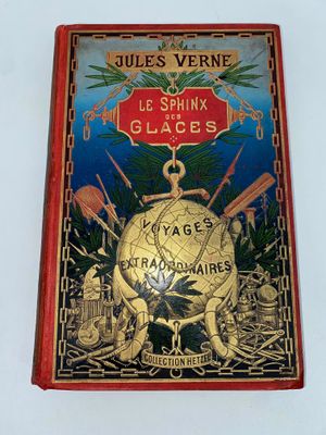 un vieux livre posé sur une surface blanche, avec une couverture rouge et un globe doré