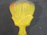 a yellow vase on a black surface with a black background