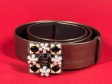 a close up of a belt with pearls on it on a red background