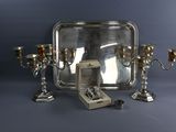 un plateau en argent sur lequel se trouvent trois bougies en argent et une bague
