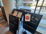 un panneau en ardoise placé devant une vitrine, sur lequel figure un menu