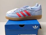 une paire de baskets Adidas posée sur une boîte bleue