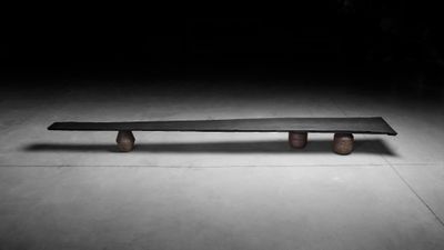 un banc en béton dans une pièce sombre, éclairé par une lumière
