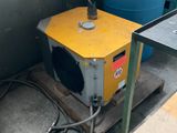 une caisse jaune posée sur une palette, à côté d'un fût bleu