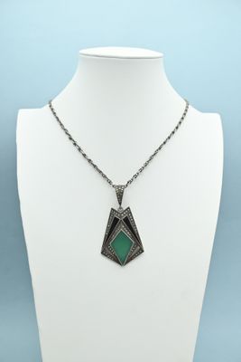a silver necklace with a green stone pendant on a mannequin