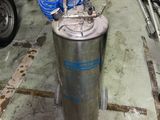 a metal tank with a blue handle on the floor