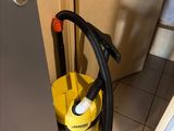a yellow bucket and a black hose in the corner of a kitchen