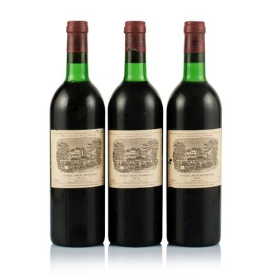 three bottles of red wine sit next to each other on a white surface