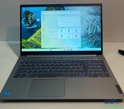 un ordinateur portable ouvert posé sur un bureau, à côté d'un stylo