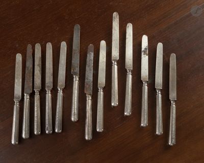 six couteaux posés sur une table, avec un couteau au milieu