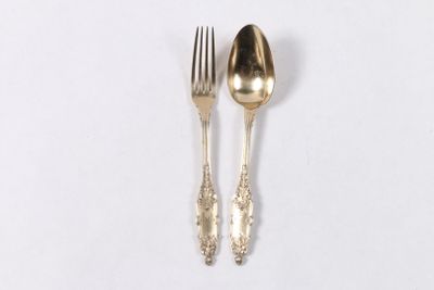 deux cuillères et une fourchette en argent sur une surface blanche