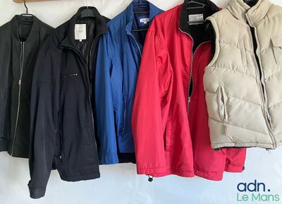 quatre vestes accrochées au mur, à côté d'un porte-manteau