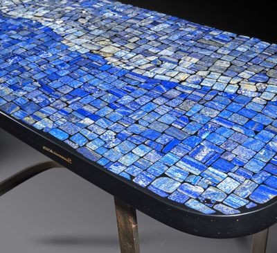 un gros plan d'une table en mosaïque bleue avec des pieds en métal