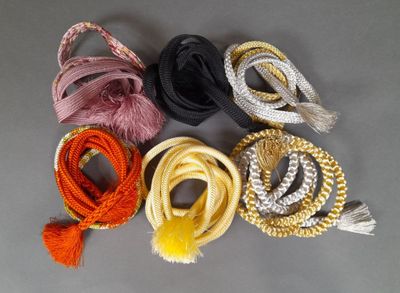 six cordes de couleurs différentes, ornées de pompons, sur un fond gris