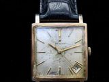 an image of a gold watch with a black leather strap