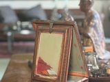 a picture frame on a table with a figurine in the background