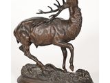 une statue en bronze représentant un cerf sur un rocher, accompagné d'une antilope
