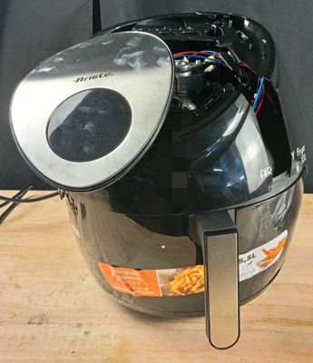 une friteuse à air chaud noire et argentée posée sur une table en bois