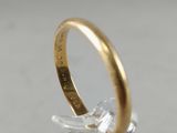 a close up of a gold wedding ring on a clear surface