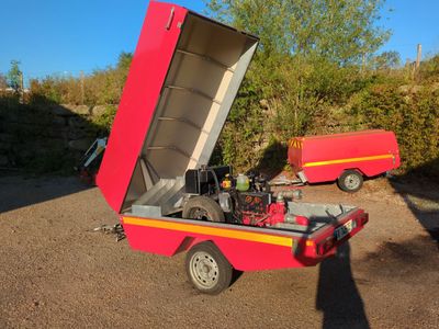 un petit camion rouge auquel est attelée une remorque rouge