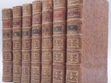 several old books are stacked on top of each other on a white surface