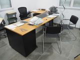un bureau avec des chaises et un ordinateur posé dessus, dans une pièce
