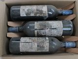 three bottles of wine are in a cardboard box on a table