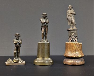 trois figurines en bronze représentant un homme et une femme, posées sur un socle