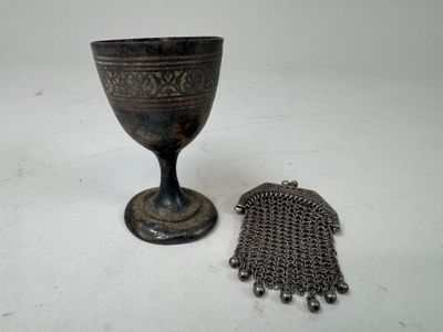 a silver cup and a chain bracelet on a table