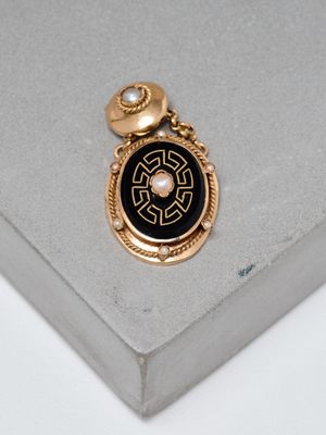 an image of a gold and black broochle on a white surface