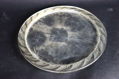 une assiette en argent posée sur une table, sur fond noir