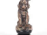 statue d'un chien avec un nœud sur la tête, assis sur un socle