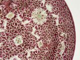 a red plate with white flowers on it on a table