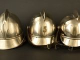 three shiny metal helmets sitting on top of a black surface