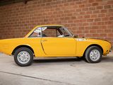 a yellow car that is parked in front of a brick wall