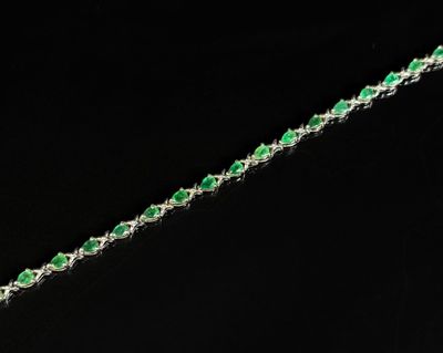 un gros plan d'un bracelet orné de pierres vertes sur fond noir