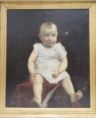 portrait d'un bébé en robe blanche, assis sur une couverture rouge