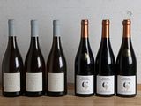 six bottles of wine are lined up on a wooden table