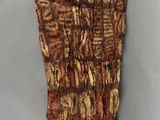 un objet tricoté de couleur marron posé sur une surface blanche
